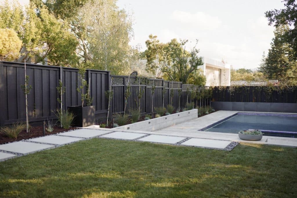 游泳池附近有黑色围栏和植物